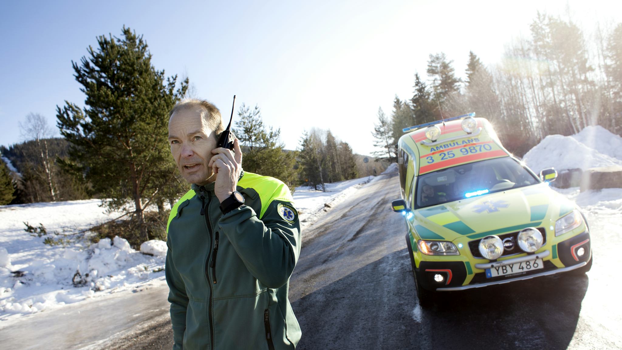 Mats kommunicerar med SOS Alarm. I ambulansen bakom vårdas ett barn med andningssvårigheter.