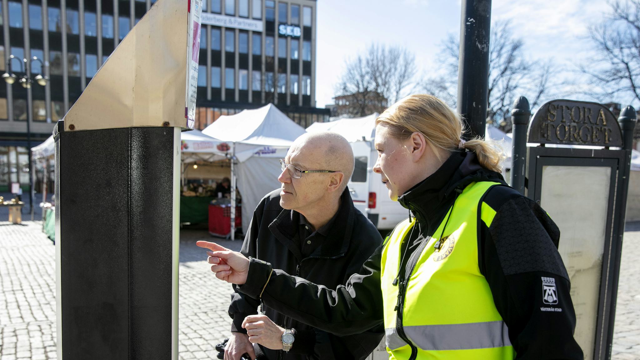 Michaela Ekström hjälper Per Hultén att förstå parkeringsautomaten.