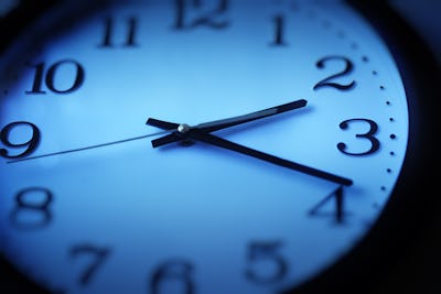 Närbild av en analog klocka som visar tiden ungefär 2.20. Klockans urtavla är blå med svarta siffror och visare.