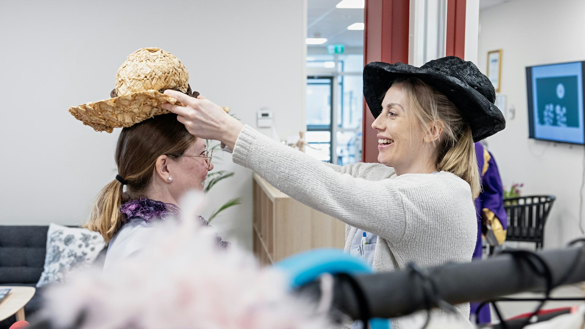 Undersköterskorna Malin Arnoldsson och Johanna Jarl provar kläder och hattar ur kostymförrådet.