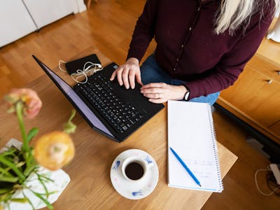 Kvinna skriver på dator och på block