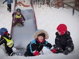 Barn leker utomhus i snön på förskola.