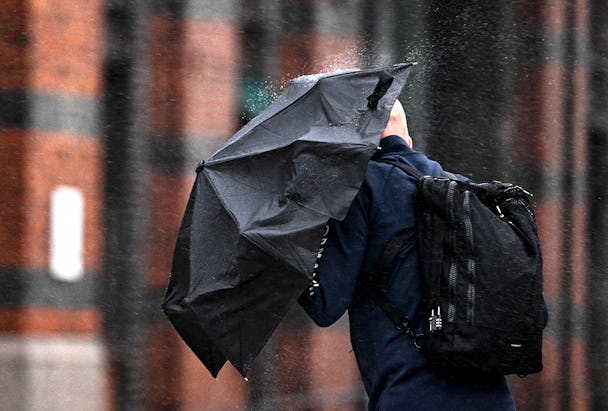 Man med paraply som skydd mot regn på tvären.
