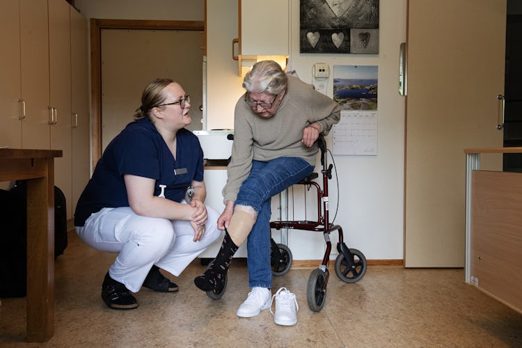 Undsersköterskan Andrea Kljajic hjälper brukaren Britt-Viol Rosenberg med stödstrumporna.