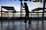 En lokalvårdar torkar golvet bland stolar och bord i lunchrummet till ett kontor med stora glasfönster mot Stockholm City.