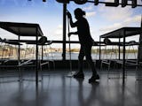En lokalvårdar torkar golvet bland stolar och bord i lunchrummet till ett kontor med stora glasfönster mot Stockholm City.