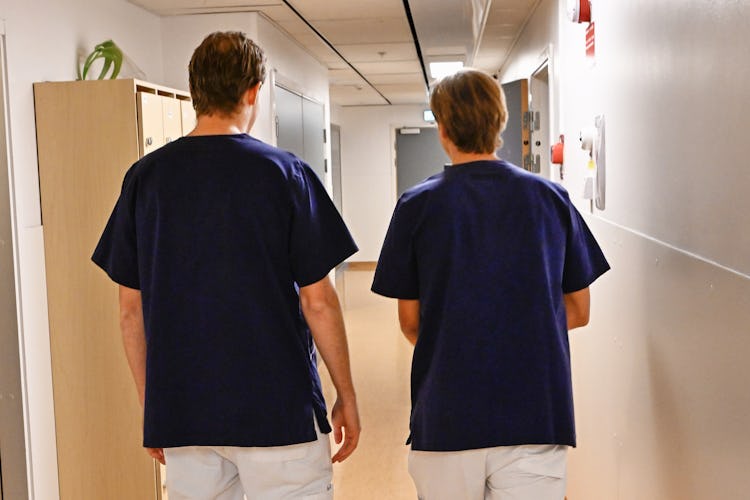 Två personer går i en korridor på ett sjukhus.