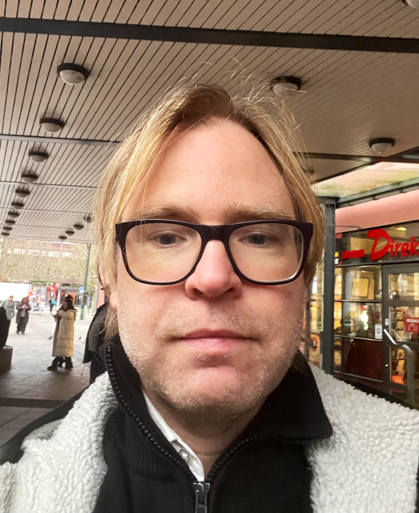 Richard Ströberg, busschaufför, i glasögon framför en butik.