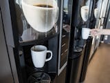 En anställd tar en kopp kaffe i från en kaffeautomat.