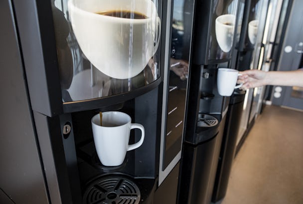 En anställd tar en kopp kaffe i från en kaffeautomat.