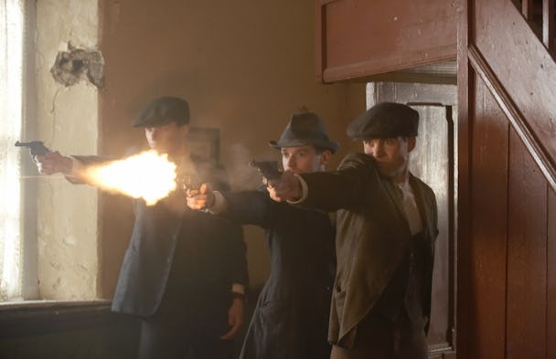 Tre män i kostymer pekar med vapen mot varandra. Scen ur filmen Frihetens pris.