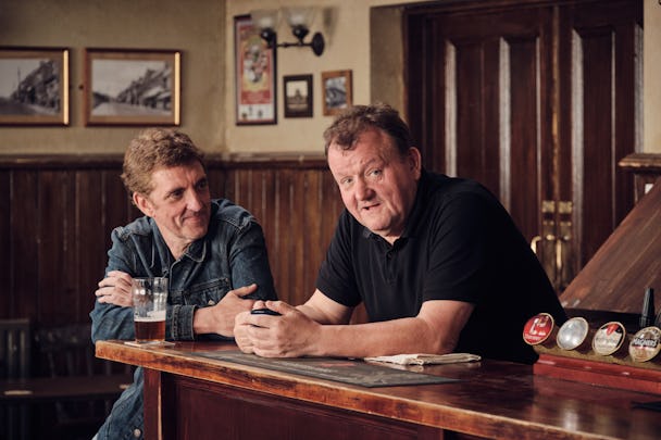 Två män sitter på en bar och pratar med varandra. Scen ur filmen The Old Oak.