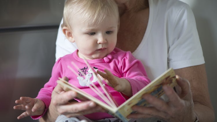 En äldre person som läser ur en bok för en bebis.