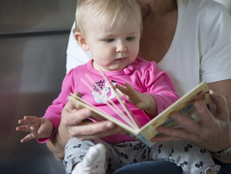 En äldre person som läser ur en bok för en bebis.
