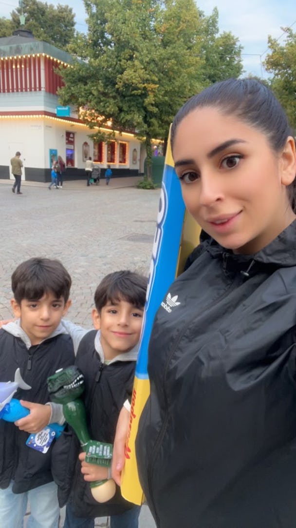 Azreen Ali och hennes barn tar en selfie framför en nöjespark.