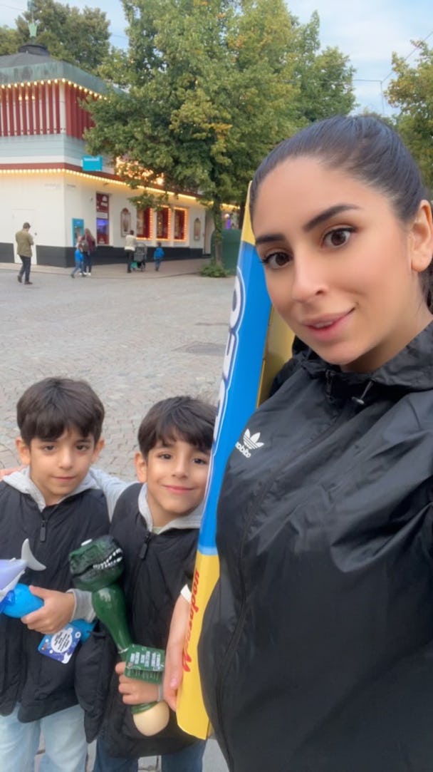 Azreen Ali och hennes barn tar en selfie framför en nöjespark.