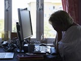 En kvinna som sitter vid ett skrivbord med en dator.