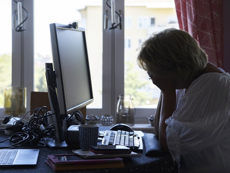 En kvinna som sitter vid ett skrivbord med en dator.