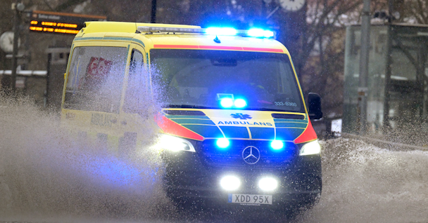 En ambulans kör genom en översvämmad gata.