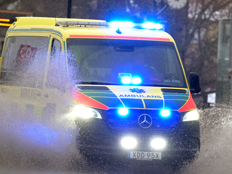 En ambulans kör genom en översvämmad gata.