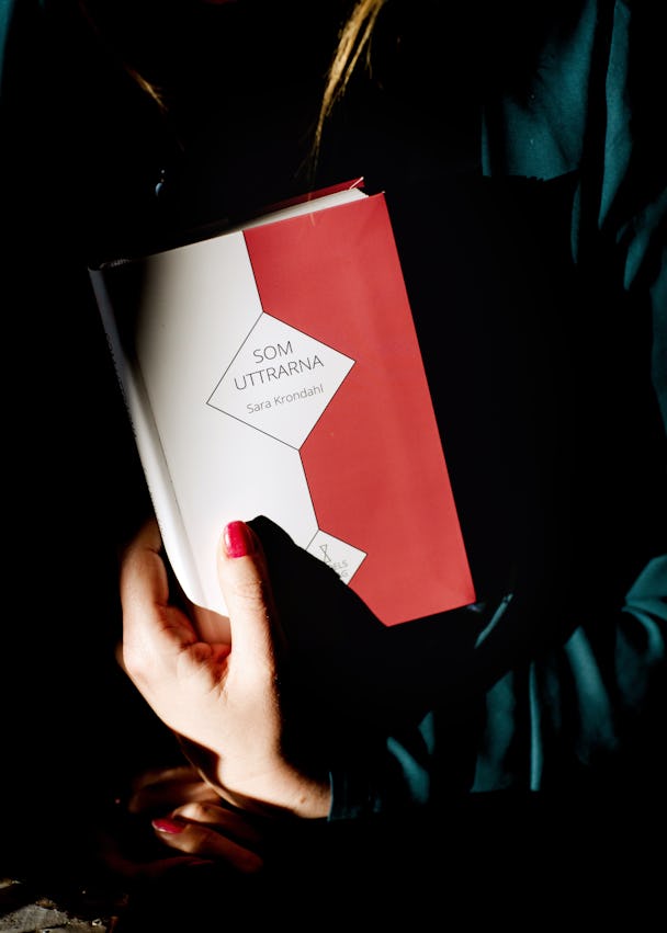 En kvinna som håller en bok med ett rött och vitt omslag.