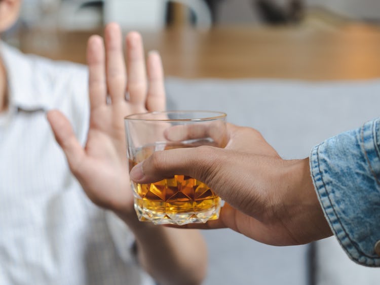En man ger ett glas whisky till en annan man som sätter stopp med handen.