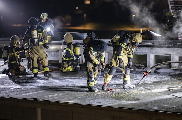 En grupp brandmän som arbetar på ett tak på natten.
