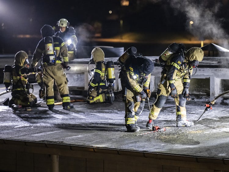 En grupp brandmän som arbetar på ett tak på natten.