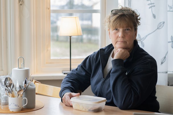 Åsa Holm som sitter vid ett bord med en kopp kaffe.