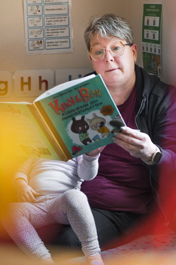 Barnskötare Cristine Jonasson som läser en bok för ett barn i ett rum.
