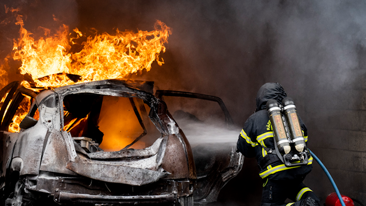 Brandman släcker ett brinnande fordon.