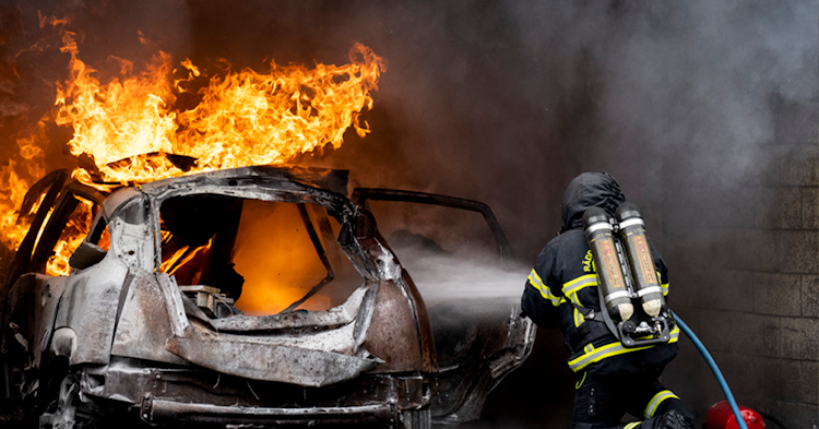 Brandman släcker ett brinnande fordon.