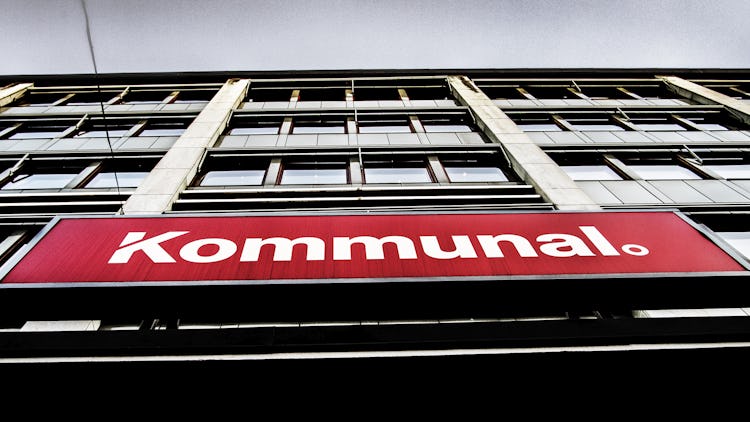 Lågvinkelvy av en byggnadsfasad med en röd skylt med texten "kommunal.