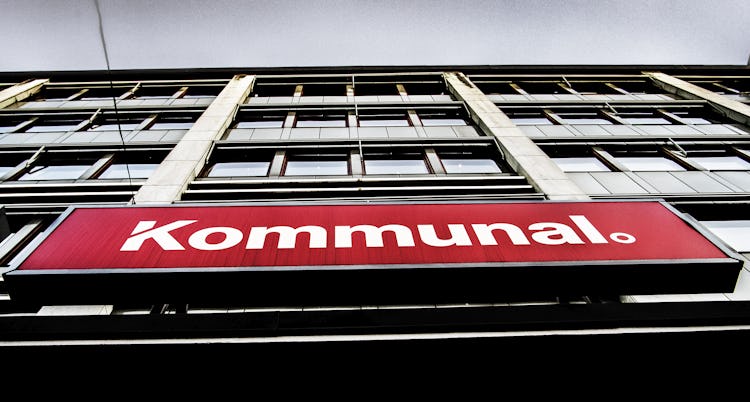 Lågvinkelvy av en byggnadsfasad med en röd skylt med texten "kommunal.