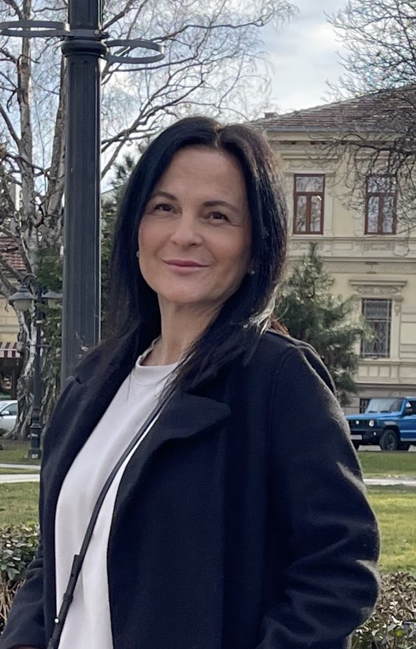 Suzana Stepanovski med mörkt hår som ler utomhus.