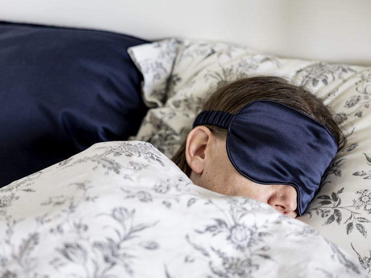 kvinna sover i säng med sovmask