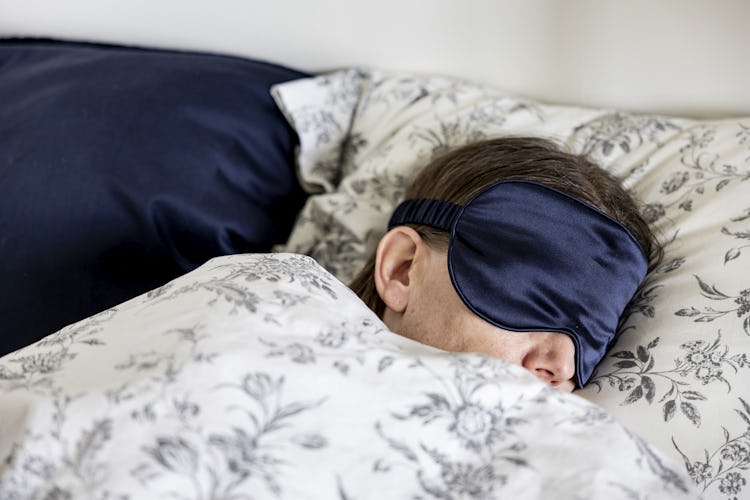 kvinna sover i säng med sovmask