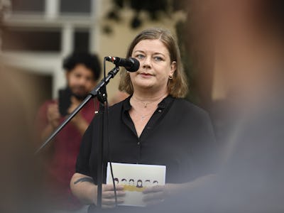 Kommunals ordförande Malin Ragnegård talar i en mikrofon under ett evenemang och håller i ett dokument; en otydlig åskådare syns i förgrunden.