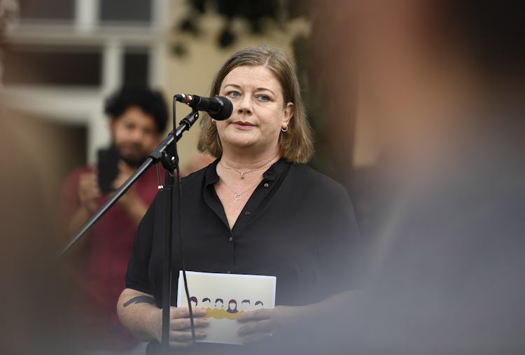 Kommunals ordförande Malin Ragnegård talar i en mikrofon under ett evenemang och håller i ett dokument; en otydlig åskådare syns i förgrunden.
