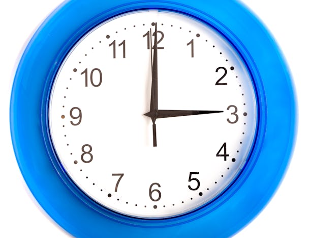 Analog väggklocka med blå ram som visar tiden 10:15, placerad mot en vit bakgrund.
