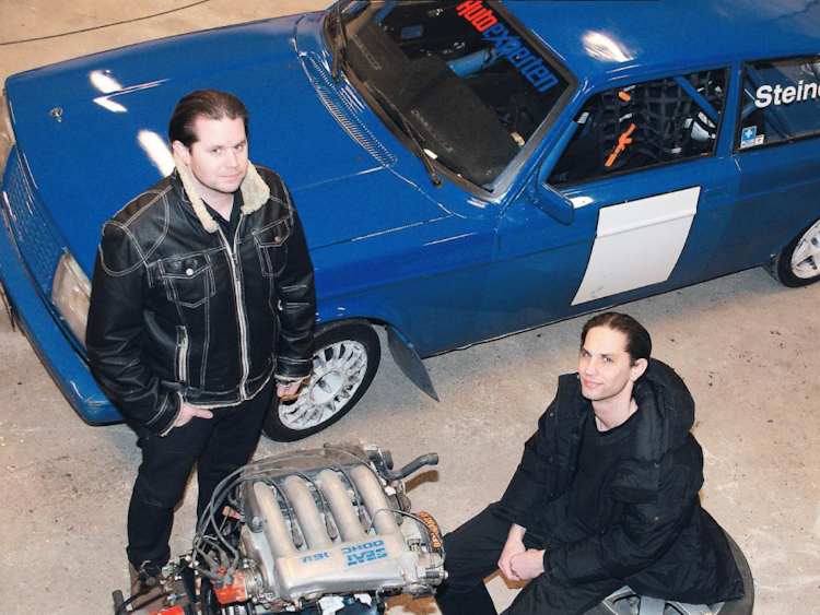 Daniel och Sebastian Steiner i verkstaden, framför en blå Volvo.