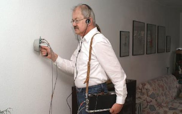 En person med hörlurar arbetar med avlyssning vid en vägg