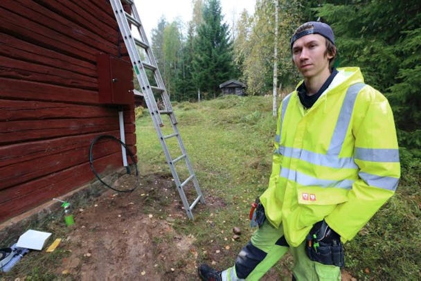 Andreas Lindqvist, i gul reflexjacka utomhus vid en röd stuga.