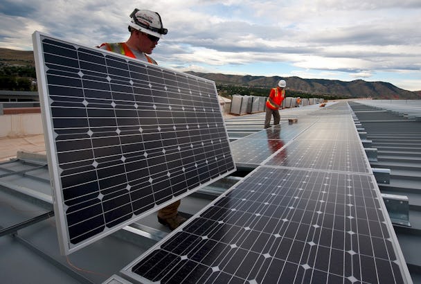 Två personer installerar solceller på ett tak