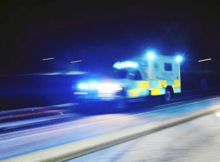 En ambulans med sirener åker på en mörk landsväg