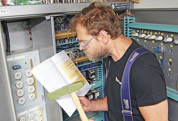 En person står framför ett proppskåp och läser en manual
