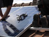 Två personer installerar solceller på ett tak