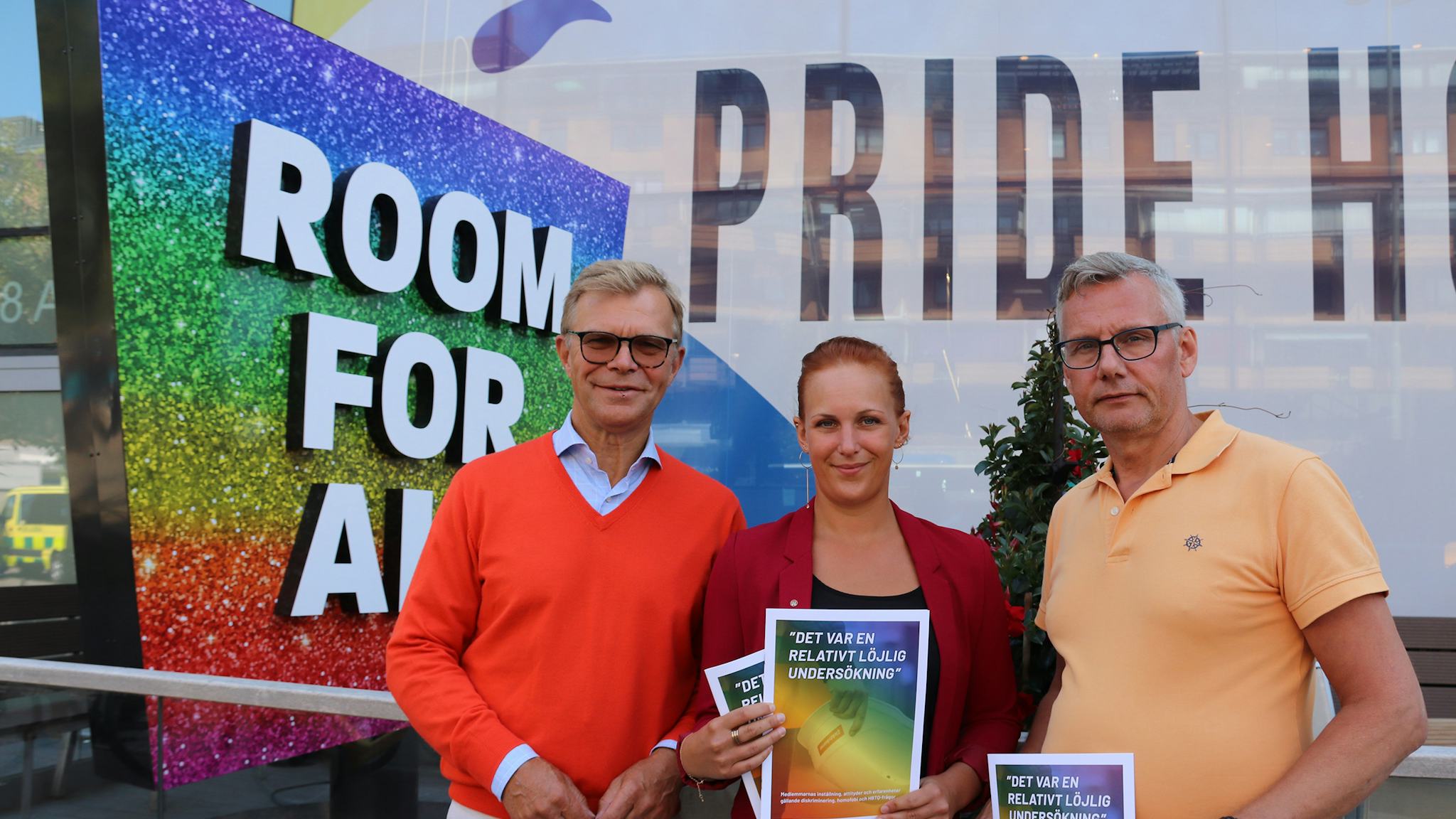 Ola Månsson, Louise Olsson och Per-Håkan Waern står framför en skylt med texten "Room for all", hållande utskrifter av rapporten i artikeln.