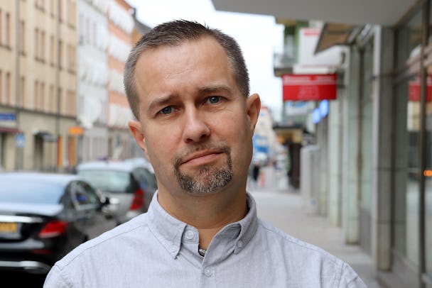 Porträttfoto av Tomas Jansson, ombudsman på Elektrikerförbundets förbundskontor, mot en stadsbakgrund.