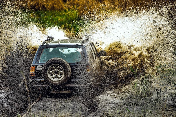 En jeep som kör offroad i en kaskad av lort och lera